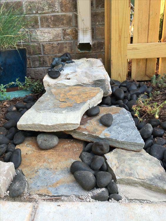 A Fun And Cool Landscaping With Big Rocks, Black Pebbles, And A Welcoming Frog #downspout #landscaping #rocks #decorhomeideas